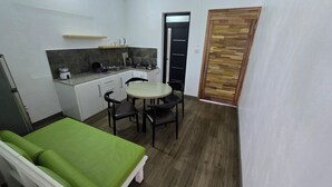 Una cocina compacta con comedor, un sofá verde y una puerta de madera.