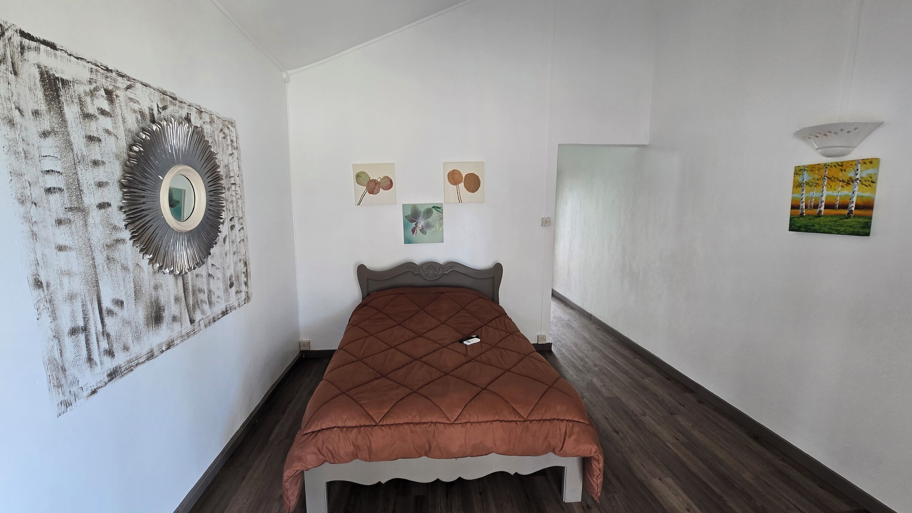 Une chambre à coucher avec un lit, un miroir et trois tableaux accrochés au mur.