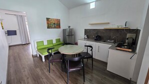 Cocina compacta con comedor, que incluye una mesa, sillas, un refrigerador, un fregadero y una estufa.