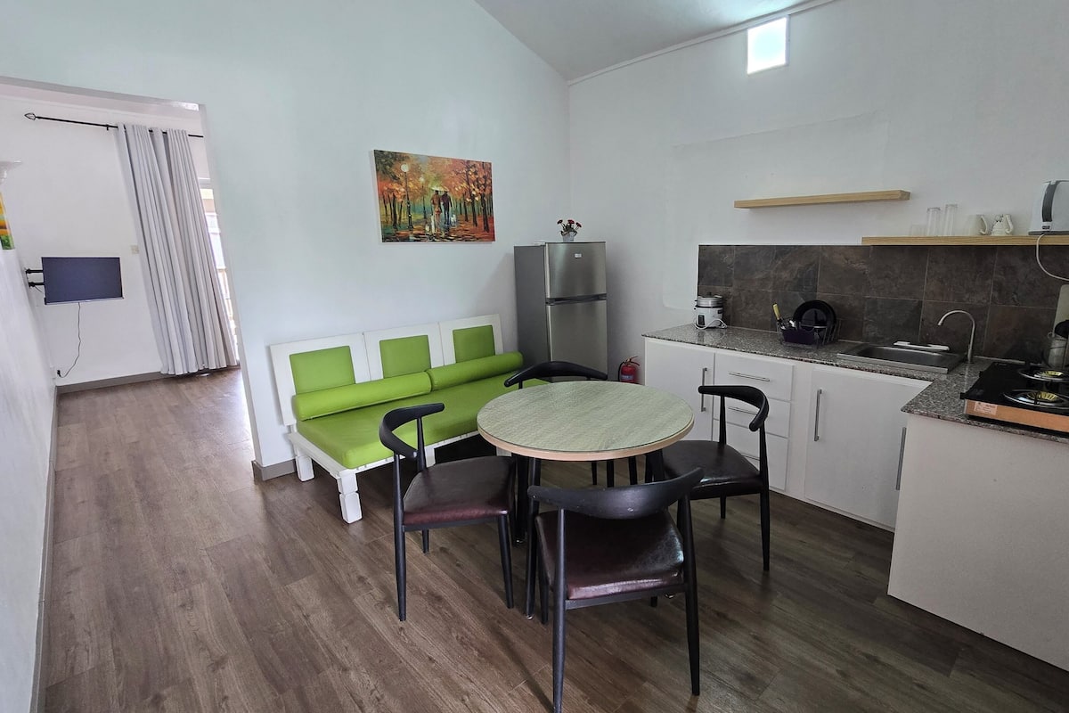 Cocina compacta con comedor, que incluye una mesa, sillas, un refrigerador, un fregadero y una estufa.