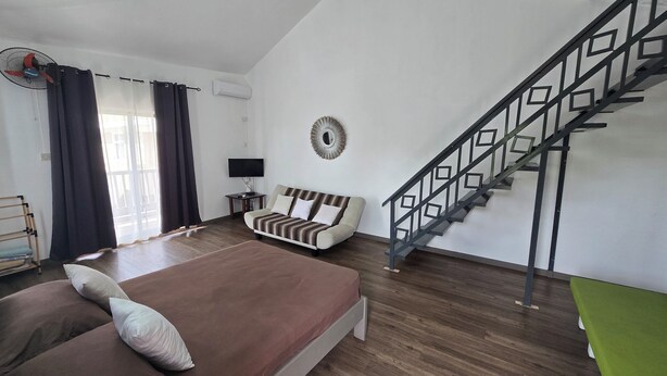Un dormitorio con cama, sofá, televisión y una escalera.