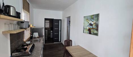 A compact kitchen with a gas stove, a sink, and a small dining table.