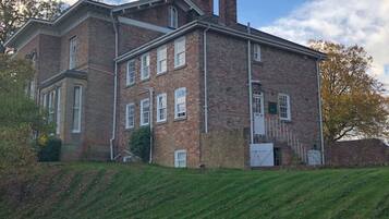 A large, two-story brick building with a symmetrical facade, multiple windows, and a prominent chimney.