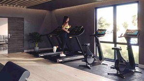 Ein modernes Fitnessstudio mit Laufbändern, Ergometer und einem großen Fenster für natürliches Licht.
