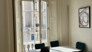 Una habitación con un ventanal grande, una mesa de comedor y un sofá verde.