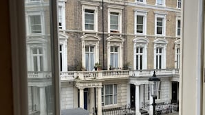 Vista de una hilera de casas urbanas tradicionales de ladrillo con detalles en blanco y múltiples ventanas, una barandilla de metal negro y una farola.