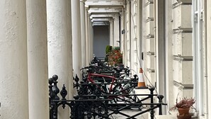 Un pasillo con columnas blancas y una fila de bicicletas estacionadas al costado.