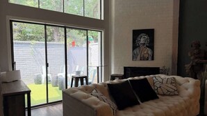 A living room with a large window, a fireplace, and a sofa. - Grand Piano, Huge Geodes, Powerful Artistic Home (Dallas)