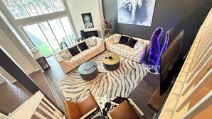 A modern living room with a sectional sofa, a zebra-patterned rug, and a fireplace. - Grand Piano, Huge Geodes, Powerful Artistic Home (Dallas)