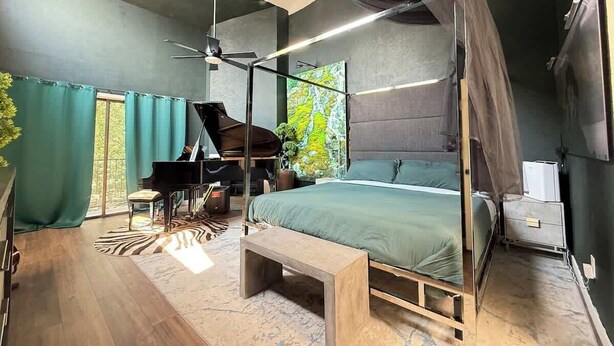A bedroom with a canopy bed, a piano, a desk, and a large window with curtains. - Grand Piano, Huge Geodes, Powerful Artistic Home (Dallas)