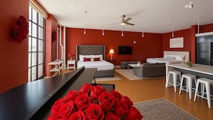 A modern hotel room with a large bed, a desk, and a seating area.