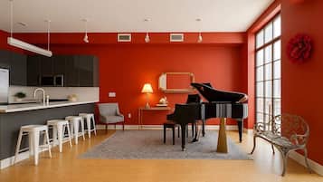 A modern kitchen with a black stove, white bar stools, and a dining area with a piano.