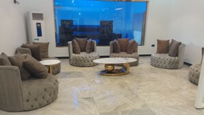 A modern living room with tufted sofas, round coffee tables, and a large window with a view.