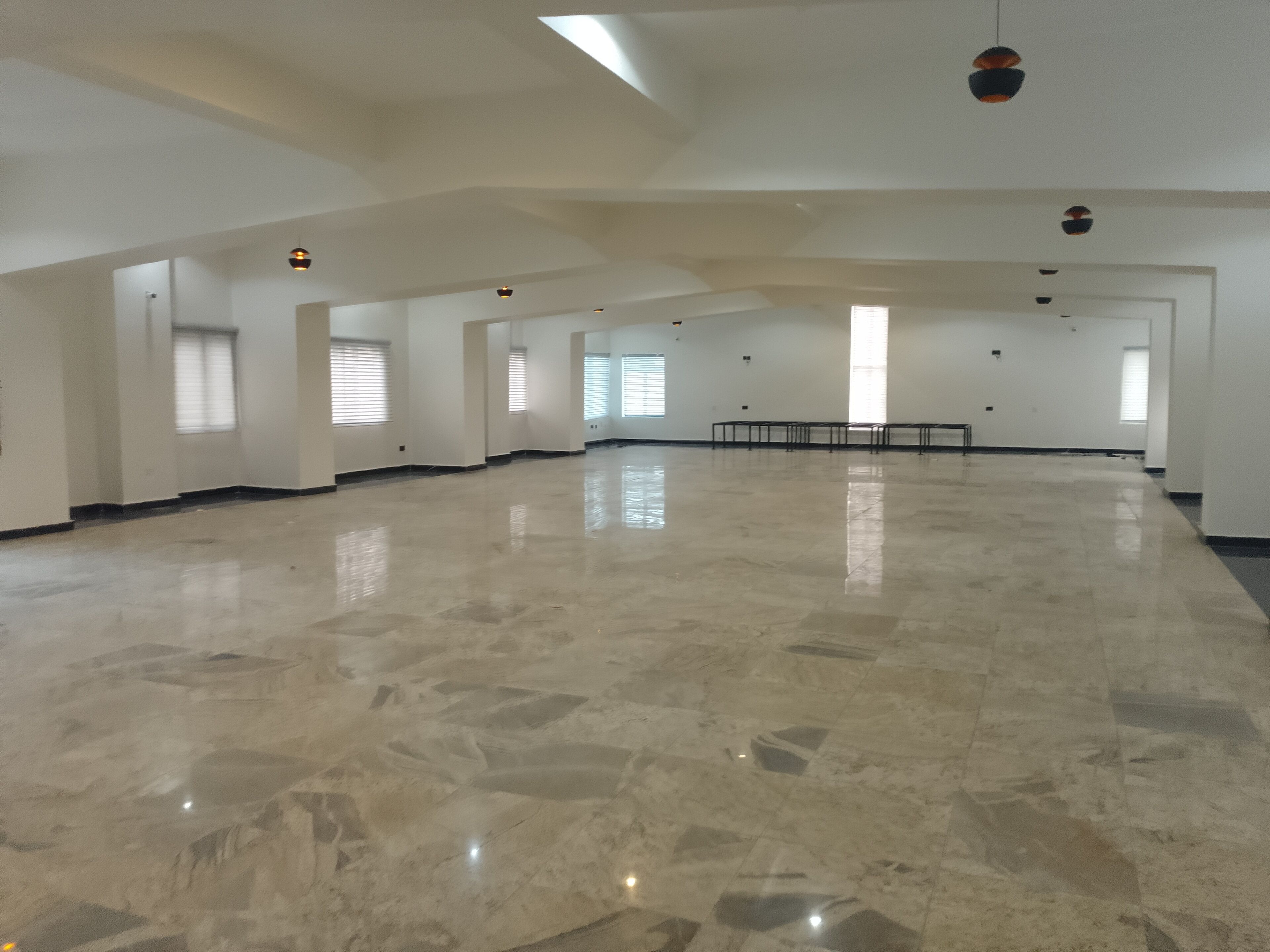 Una habitación amplia y vacía con piso pulido, ventanas grandes y techo alto.