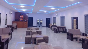 A modern lounge area with seating arrangements, a bar, and vending machines.