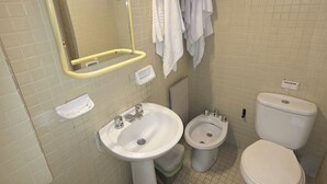 Un baño con lavamanos, dos inodoros, un bidé y un espejo con luces.