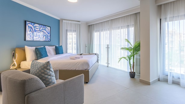A modern hotel room with a large bed, a seating area, and a potted plant. - CityZen - Boutique Studios in Achrafieh (Beirut)