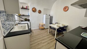 Una cocina pequeña con pileta, estufa y mesa de comedor.