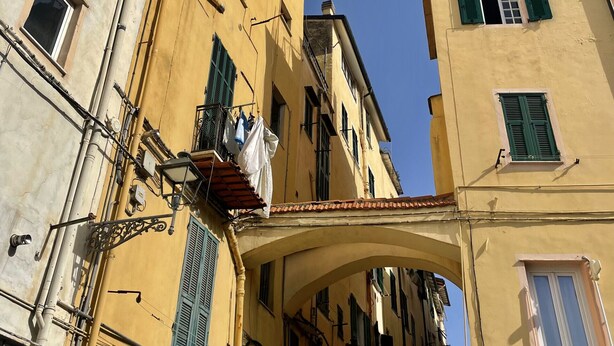 Una calle estrecha con edificios que tienen balcones y toldos.