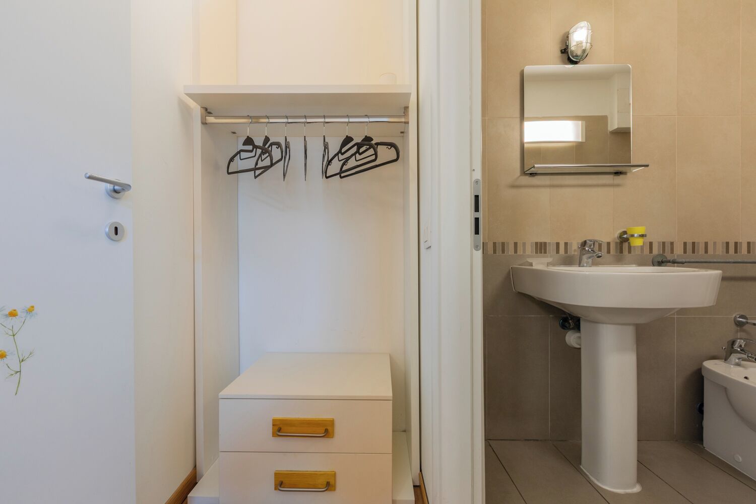 Une salle de bain avec un lavabo blanc, un miroir, un porte-serviettes et un petit meuble.