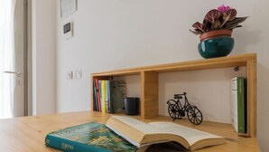 Una mesa de madera con un libro abierto titulado 'TORINO UN PO', una planta en maceta y una estantería con libros y una bicicleta.