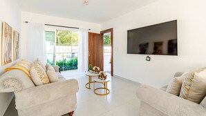 Una sala de estar moderna con dos sofás, un televisor montado en la pared y una mesita con objetos decorativos.