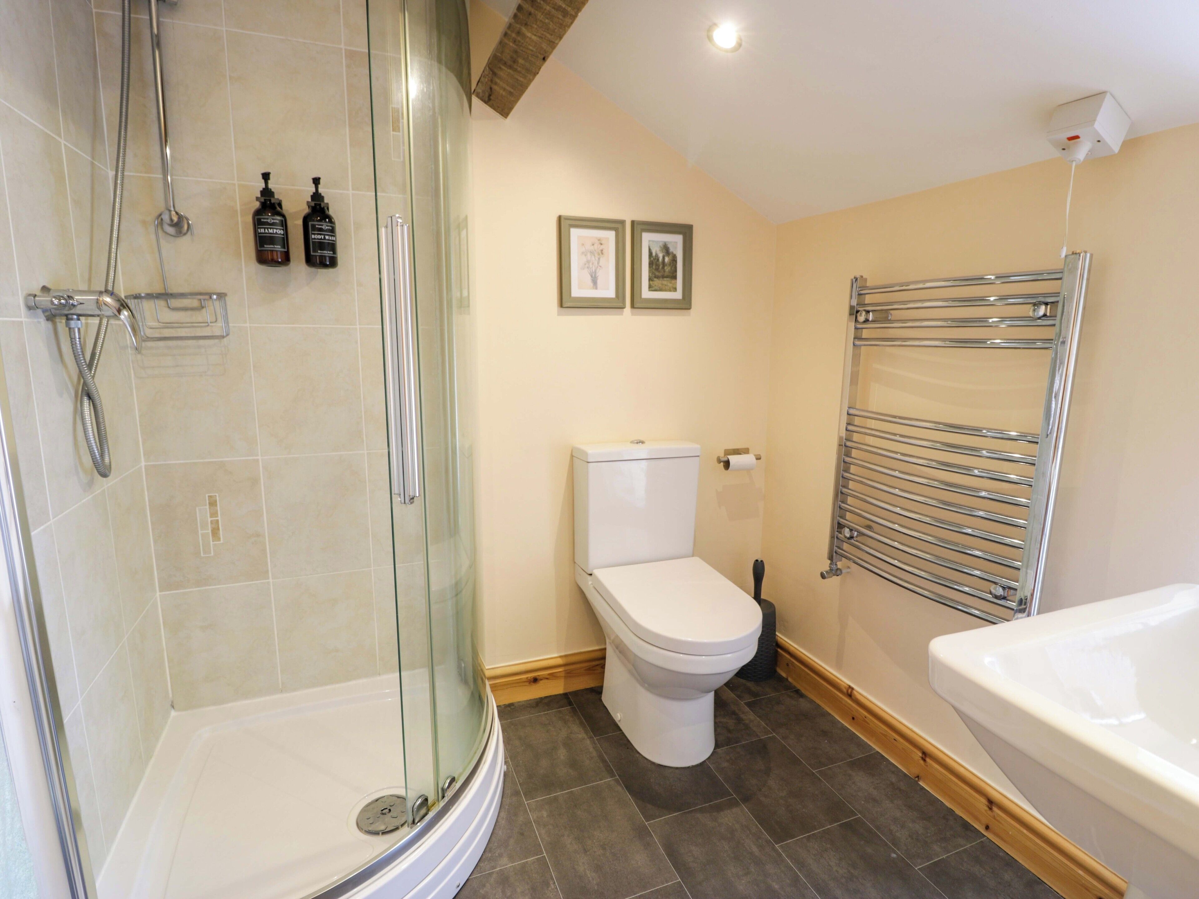 Een badkamer met een douche met glazen wand, een toilet en een bad.