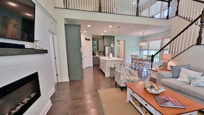 A spacious living area with a fireplace, a dining table, and a sofa. - Coastal Club* Resort House w 5 BR, 3.5 Baths - Sleeps 12 (Lewes)