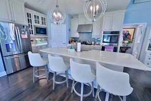 A modern kitchen with white cabinetry, stainless steel appliances, and a central island with bar stools.