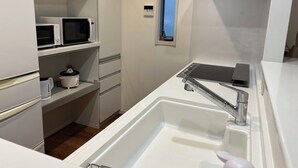 A compact kitchen with a sink, two microwaves, a kettle, and a window. - One private house! Max. 9 people with parking! 3 min walk from Yoyogi, 2 min by train from Shinjuku/Harajuku, 5 min from Shibuya, 7 min from Roppongi Hotel Like Yoyogi Homes (Sibuya-ku)