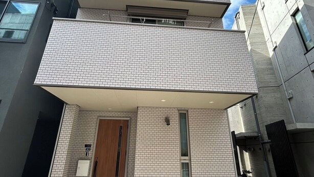A two-story building with a tiled facade, a wooden door, and a small porch area. - One private house! Max. 9 people with parking! 3 min walk from Yoyogi, 2 min by train from Shinjuku/Harajuku, 5 min from Shibuya, 7 min from Roppongi Hotel Like Yoyogi Homes (Sibuya-ku)