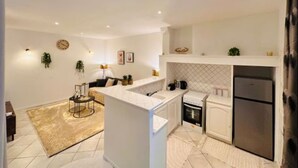 Una cocina moderna con armarios blancos, horno empotrado y refrigerador de acero inoxidable.