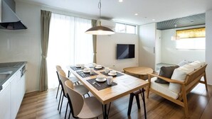 A modern kitchen with a dining area, a sofa, and a TV.