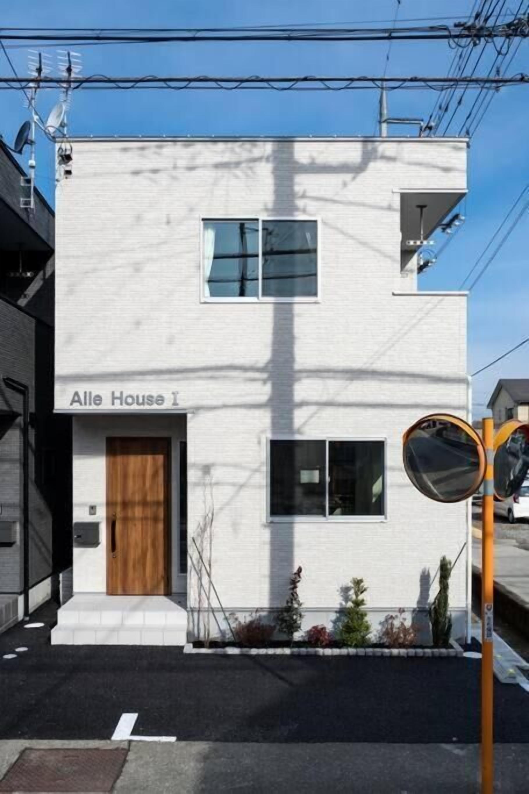 A modern two-story building with a sign reading "Alle House I".