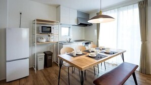 A modern kitchen with a dining area, white appliances, and a large window with curtains.