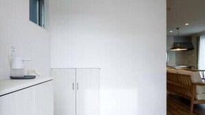 A modern kitchen with white cabinets, a wooden countertop, and a built-in shoe rack.