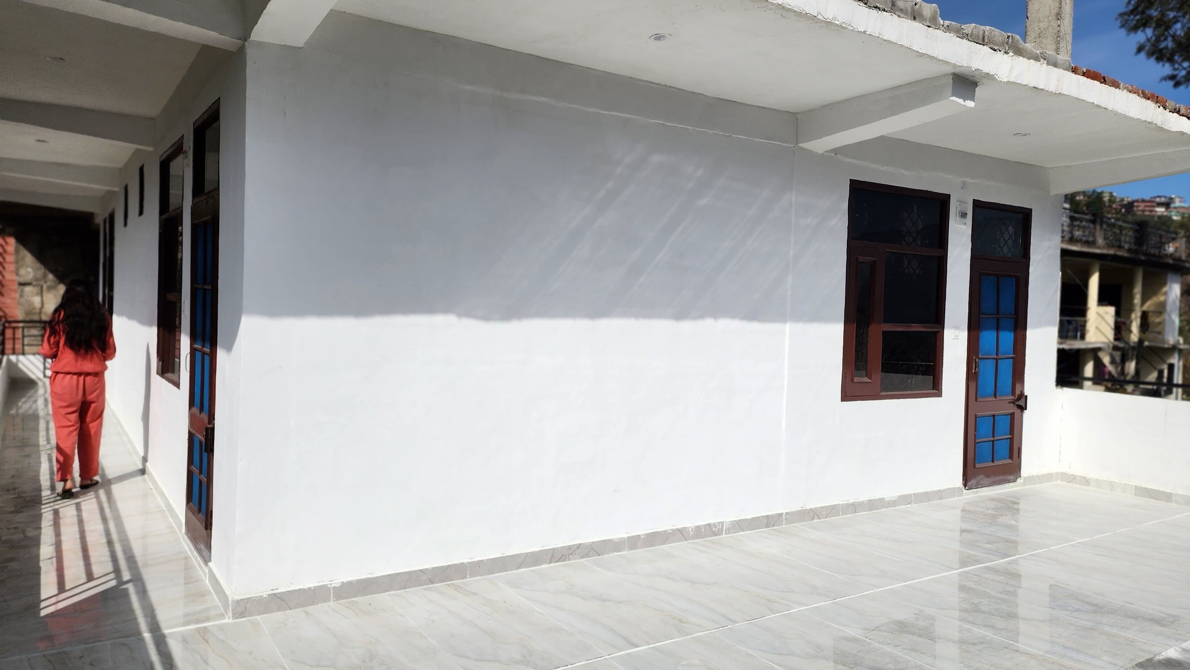 A building with a clean, white exterior, a tiled floor, and two windows with brown frames.