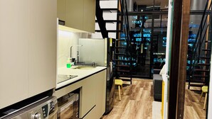 Eine moderne Küche mit integriertem Waschmaschine, einem großen Fenster und einer Treppe, die in eine untere Ebene führt.