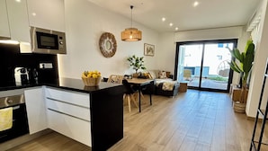 A modern kitchen with a central island, a dining area with a table and chairs, and a large window providing a view of the outside.