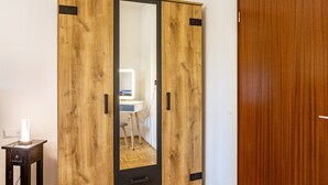 Une armoire en bois avec un miroir, une petite table avec une lampe et une porte en bois.
