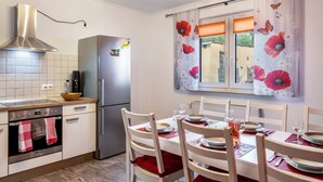 Une cuisine équipée d’une cuisinière, d’un four, d’un réfrigérateur et d’une table à manger pour quatre personnes.