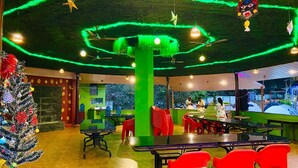 Un restaurante con paredes verdes, sillas rojas y un árbol de Navidad.