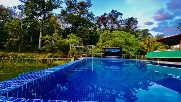 Una piscina con un letrero que dice "KINGFISHER ZONE STATION" rodeada de árboles.