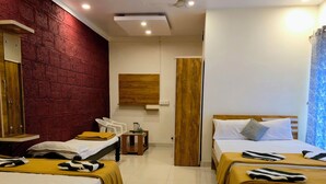 Una habitación de hotel con dos camas, un armario de madera, una pared de ladrillo rojo y un ventilador de techo.