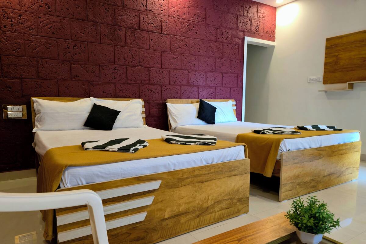 Een hotelkamer met twee bedden, een houten hoofdeinde, een klein tafeltje, een stoel en een potplant.