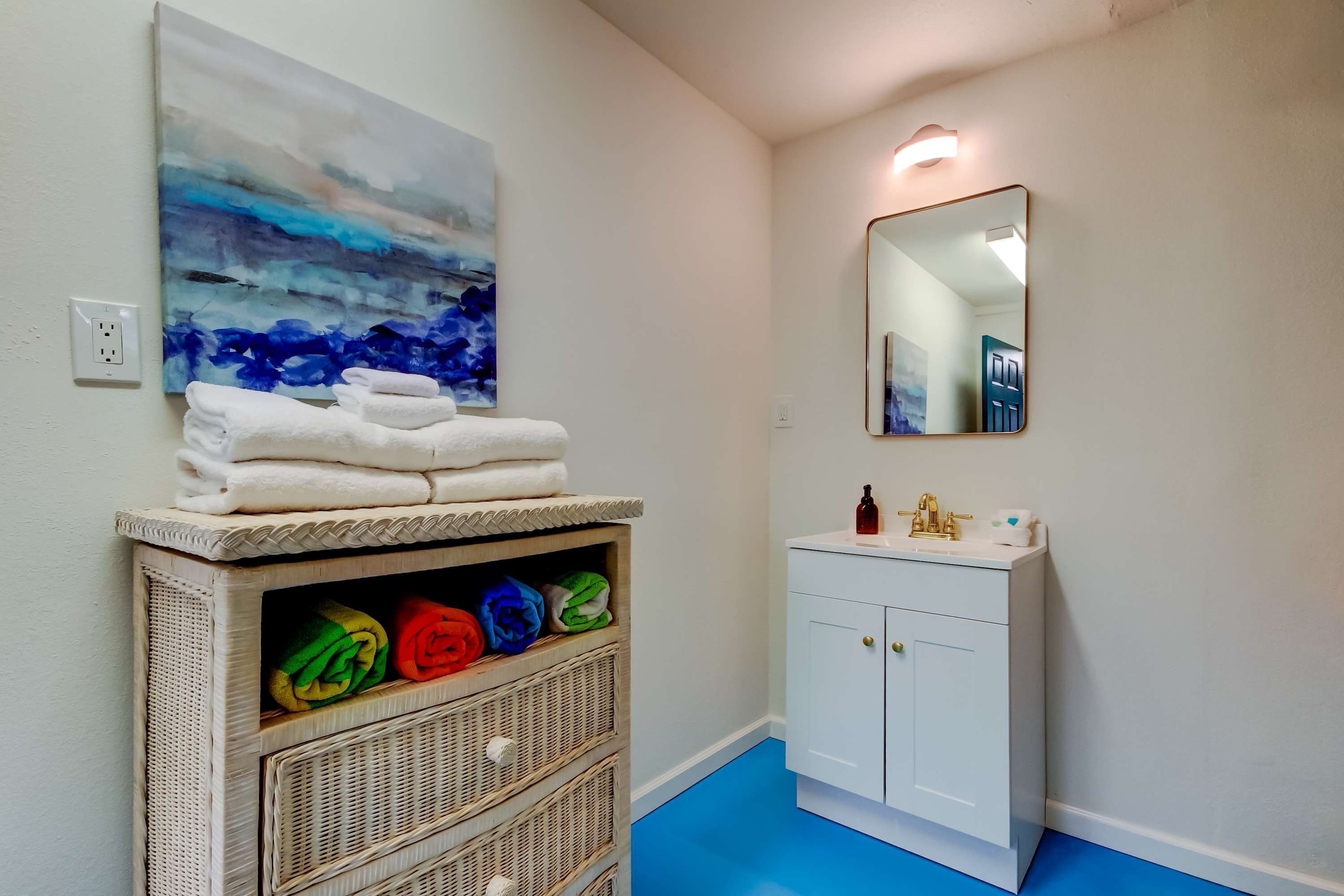 Un bagno con un lavandino bianco, uno specchio e un quadro appeso al muro.