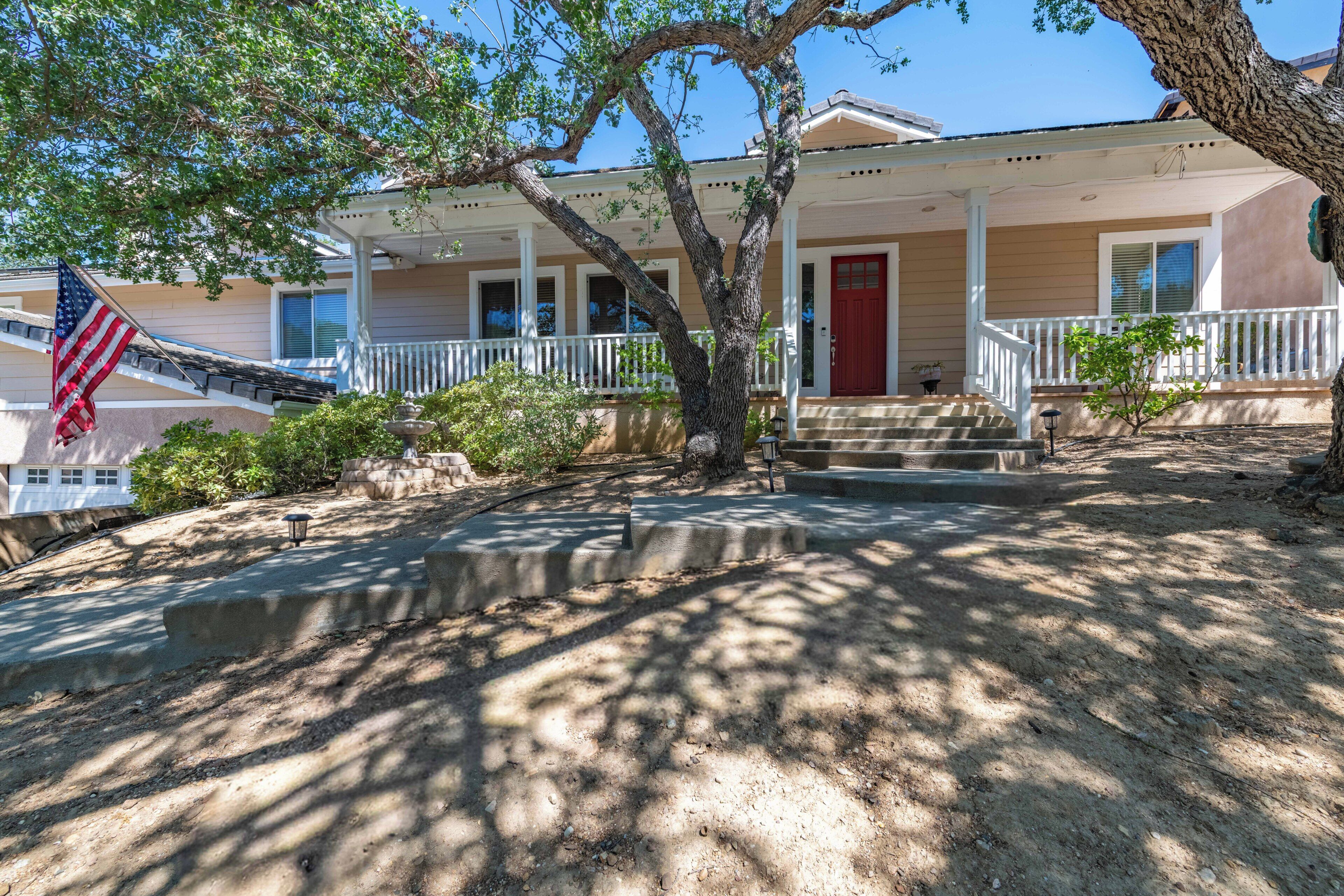 Charming single-story home with welcoming front porch, mature shade trees, and classic architectural details in a peaceful neighborhood setting.