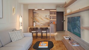 A modern living room with a sofa, coffee table, and artwork. There is a dining area with a table and chairs. The room has wooden shelves and a large painting on the wall.