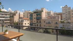 A balcony with a view of a cityscape, a wooden table, and a potted plant.