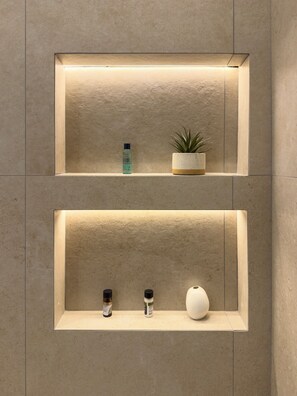 Dos repisas rectangulares montadas en la pared, cada una con una planta pequeña en maceta, una botella y un adorno.
